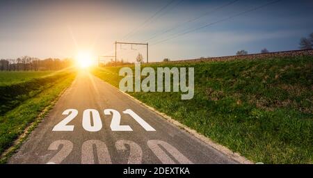 Neujahrskonzept mit dem Jahr 2021, das`s der Mitte einer Asphaltstraße bei Sonnenuntergang gedruckt wird. Stockfoto